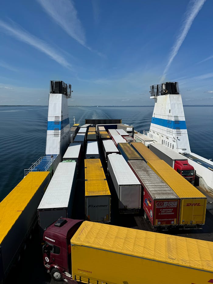 about-01 Rows of cargo trucks loaded on a ferry ship crossing the sea under a clear sky.
